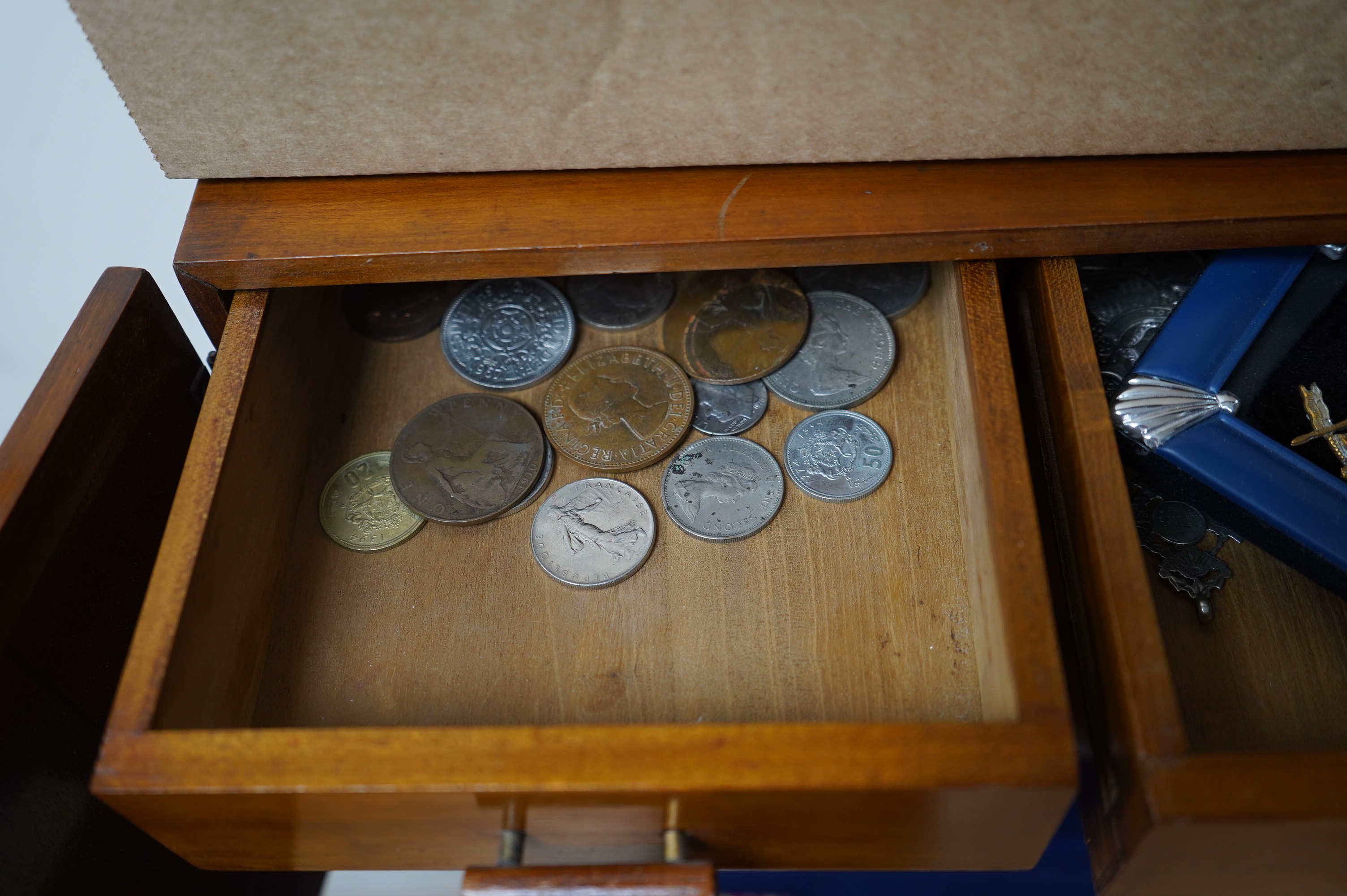 Coins, medals, medallions and badges, mainly 20th century British and European issue contained within a wooden cabinet, together with three leather boxes with padddd and lined interiors. Condition - fair.